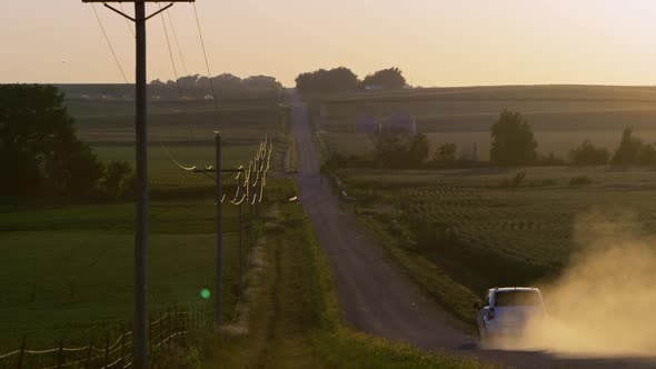 Slow motion static view of car driving down dirt road in Wahoo, Nebraska.