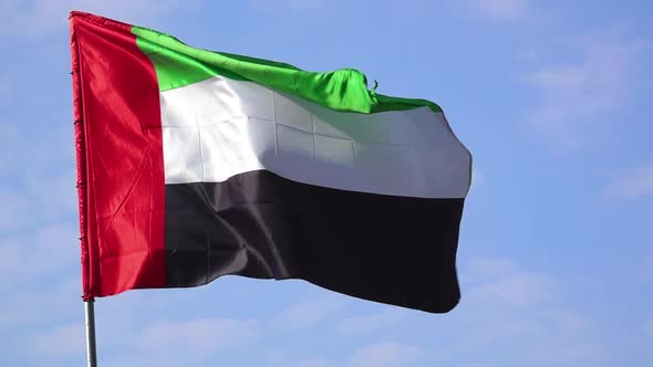 National Flag of United Arab Emirates (UAE) on a Pole Waving in Wind Against Clear Blue Sky