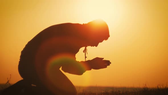 Silhouette Young Man Praying Outside at Beautiful Sunset. Male Asks for Help Finding Solace in Faith