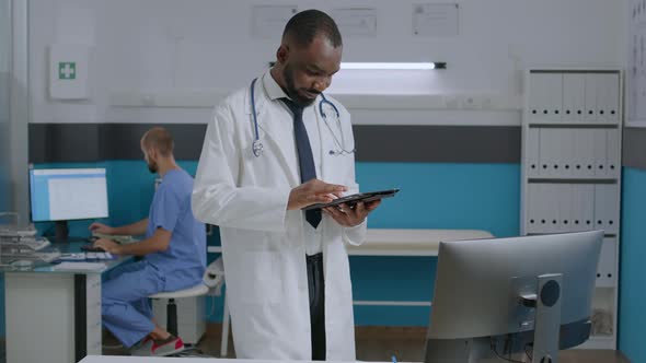 African American Therapist Doctor Holding Tablet Computer Checking Disease Symptoms Report