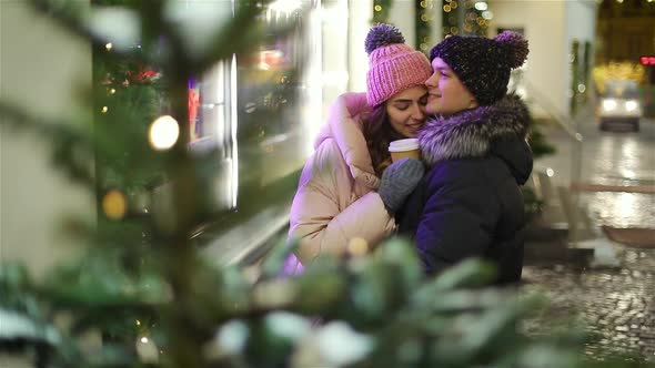 Young Couple Walking on Evening Street in Winter. Christmas Shop Window