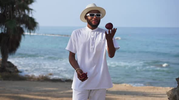 Happy African American Man Juggling Red Apples Crossing Hands Looking at Camera Posing at