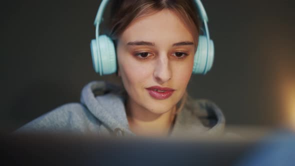 Pensive woman in headphones looking at laptop