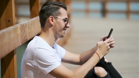 Man Is Reading Text Message on Mobile Phone While Sitting in the Park.