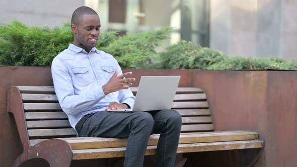 Cheerful African Man Doing Video Call on Laptop Outdoor