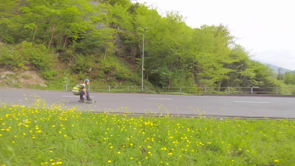Young men longboard skateboarding downhill on a rural country road.