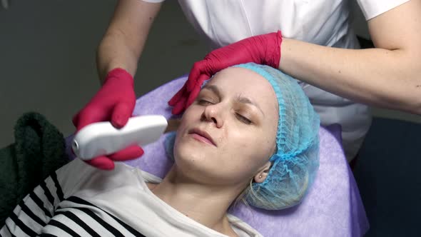 Professional beautician skin treatment with ultrasonic machine. Slow motion.