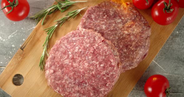 Raw Burger Meat Slowly Rotates on a Wooden Board.