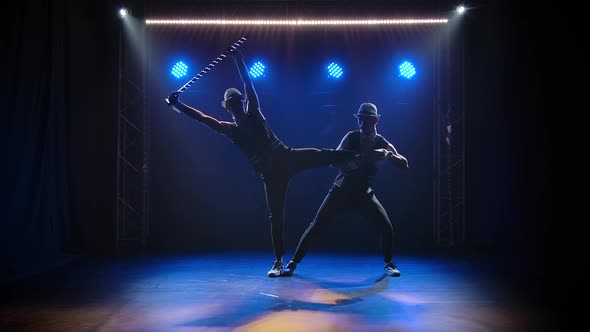 Group of Male Gymnasts Perform Acrobatic Stunts on Balancing. Silhouettes of Two Men on a Black