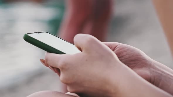 Young Woman Uses a Smartphone on the Beach