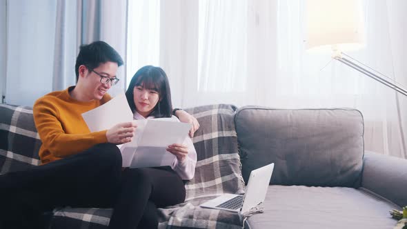 Happy Young Couple Relaxing on the Couch and Looking at Papers