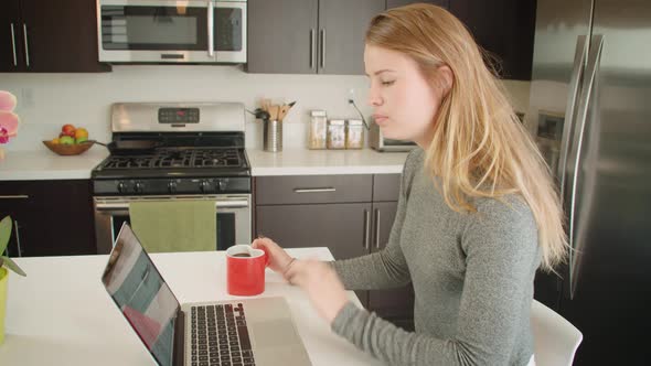 Attractive woman working from home while sitting in her kitchen