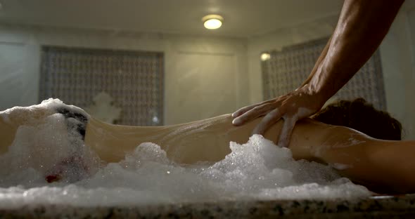 A Woman Lies in a Turkish Bath-in a Hamam on a Huge Table, a Man Poured Foam All Over Her, Massages