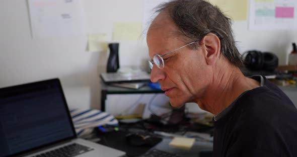 A teacher in a messy school office giving an online remote class to his students via a video livestr