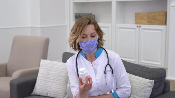 Young Woman Doctor Wearing Protective Mask Prescribing Medicine to Patient During Home Care Visit
