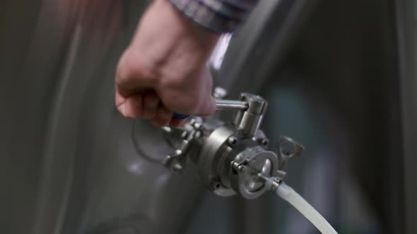 Close-up of a Male Brewer Opening a Tap for Dispensing Beer From a Beer Tank To a Keg