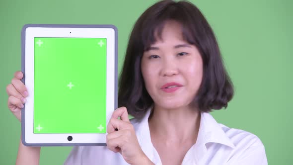 Face of Happy Asian Businesswoman Talking While Showing Digital Tablet