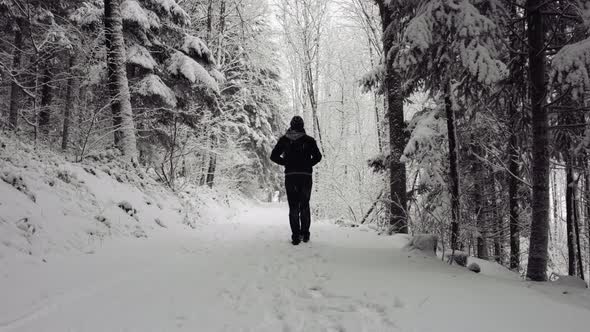 Anonymous man walking on snowy path