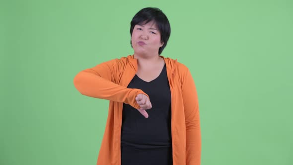 Stressed Young Overweight Asian Woman Giving Thumbs Down for Gym
