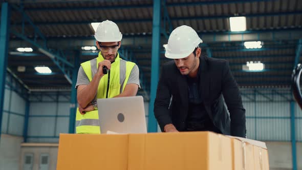 Two Factory Workers Working and Discussing Manufacturing Plan in the Factory