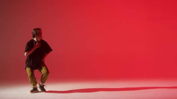 Young Woman Wearing Black Tshirt Dancing Contemporary on Red Neon Background in Studio