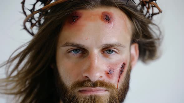 Jesus in a Crown of Thorns with Wounds on Face Looks Into the Camera