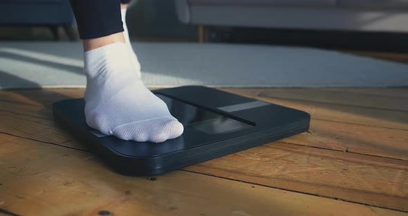 Lady Stands on Digital Scales to Check Weight on Floor