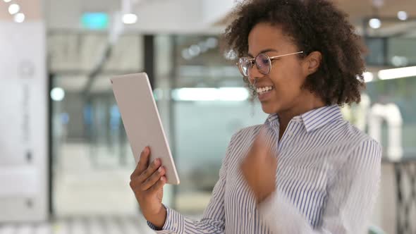 African Businesswoman Celebrating Success on Tablet 