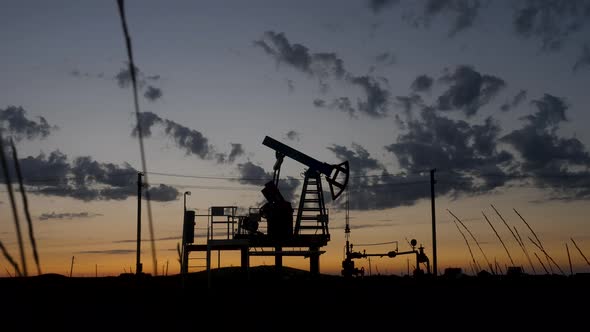 Oil Rig Stands in a Field at Sunset and Extracts Minerals