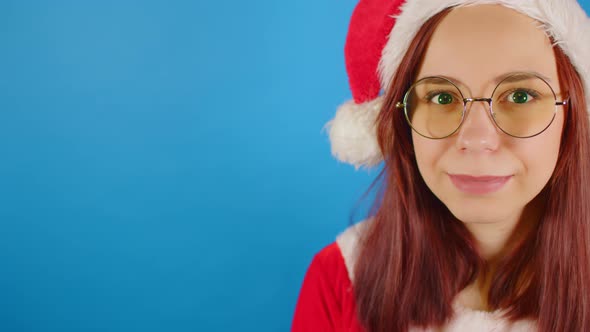 Female in christmas hat, eyeglasses looking at camera and smiling