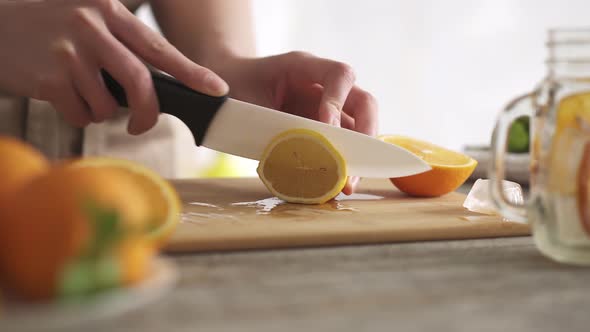 The Hostess In The Kitchen Cuts A Slice Of Lemon. Cooking Cool Lemonade At Home In The Kitchen