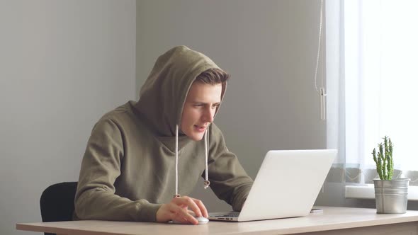 Young Programmer Working on a Laptop Makes a Winning Gesture After a Successful Transaction