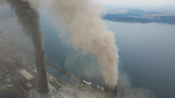 Aerial view of coal power plant high pipes with black smoke moving up polluting atmosphere.