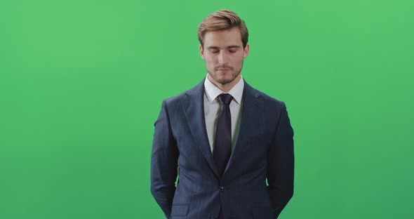 Businessman in a Suit Standing in Green Room and Looks at the Camera, Chroma Key Background, a Man