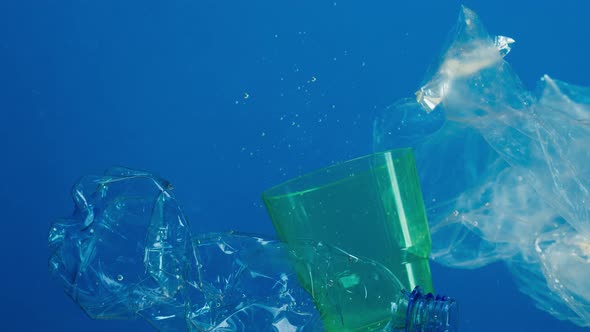 Closeup of Plastic Glasses and Bottles in Ocean Water Pollution Concept