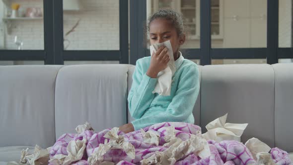 Sick Girl with Cold Blowing Nose in Tissue at Home