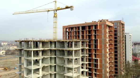 Aerial view of concrete frame of tall apartment building under construction in a city.