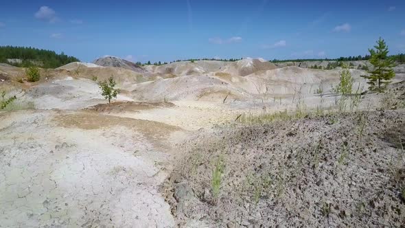 Camera Moves Fast Low Above Clay Quarry Slope Tops and Pond