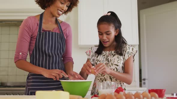 African american mother and daughter baking together in the kitchen at home