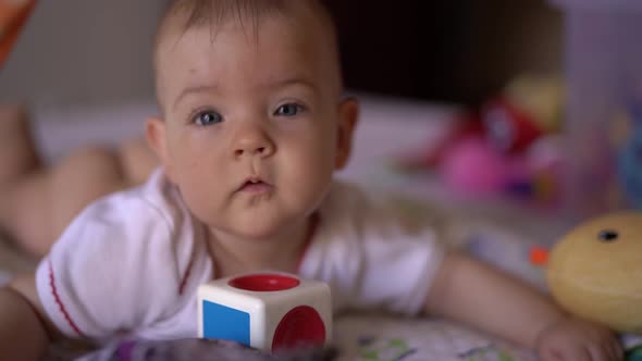 Baby Lies on His Tummy on the Bed and Turns His Head