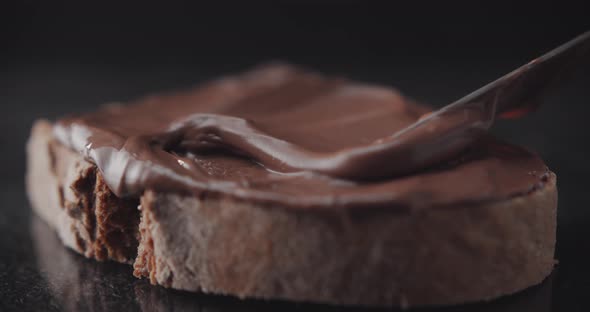 Spreading chocolate cream on a slice of rye bread.Pastry close up shot.