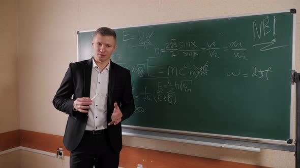 A Portrait of a Male Professor Standing Against a Blackboard with Chalk