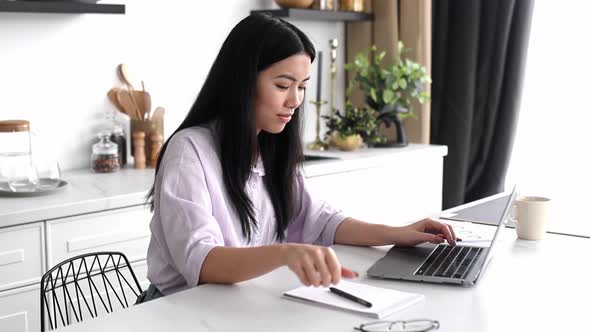 Positive Pretty Smart Chinese Brunette Girl Designer Freelancer or Student in Shirt Sits at Home in