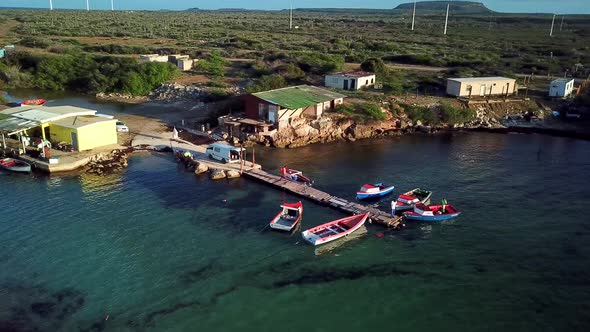 Aerial orbit of a small dock with poor houses around, fishing bay, Kanoa Beach, Curacao, Dutch Carib