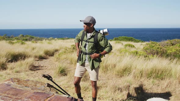 African american man hiking in countryside by the coast taking a rest