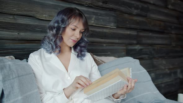 Slow Motion of Beautiful Young Lady Wearing Pajamas Reading Book in Bed