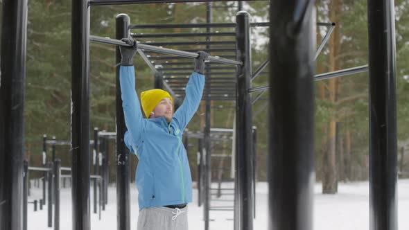 Man Exercising on Workout Pull-Up Bar Outdoor in Winter