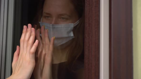 Two girls, sisters touch their hands with their palms through a glass window,