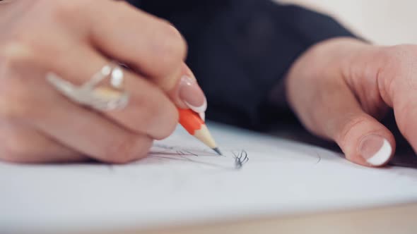 Woman's hand with a beautiful ring of a designer is drawing sketch of dress in atelier.