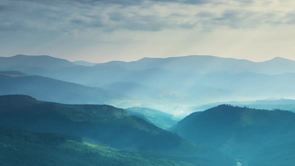 Sunbeams and Clouds Over Wooded Mountains